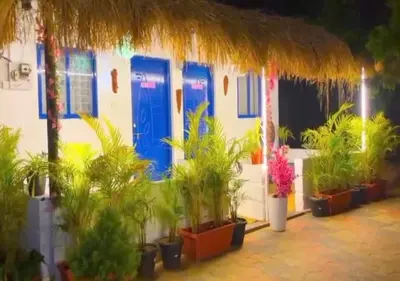 a building with blue doors and a bunch of plants at The Wildcamp - Coorg in Kushālnagar