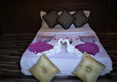a bed with two swans laying on it at The Wildcamp - Coorg in Kushālnagar