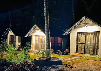a house with a palm tree in front of it at The Wildcamp - Coorg in Kushālnagar