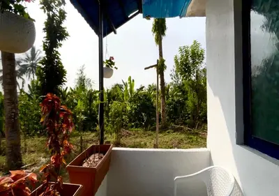 a view of a garden from a window with a chair at The Wildcamp - Coorg in Kushālnagar