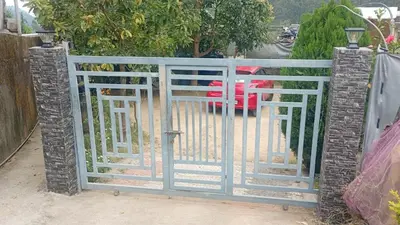 an open gate with a red car behind it at Enjoy home stay in Vattavada