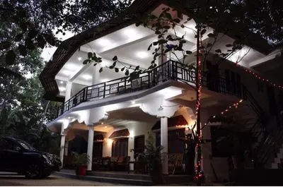a white house with a porch with lights on it at The H and S Stays in Madikeri
