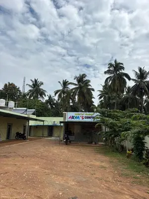 a building with palm trees in front of it at Aryas comforts Sri Rangapattana in Nāganahalli
