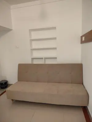 a brown couch in a room with a white wall at Ivory Suites County in Kozhikode