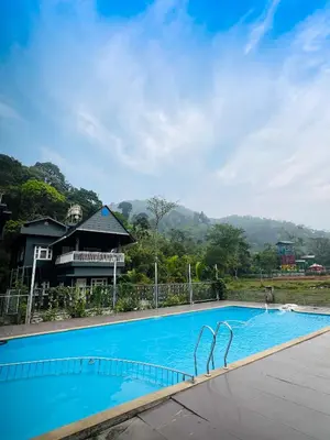 a large blue swimming pool in front of a house at oakden lakkidi villa vythiri villa wayanad in Vythiri