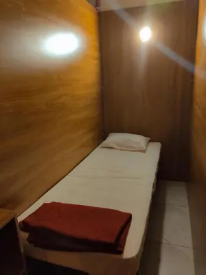 a small bed in a room with a wooden wall at Thekkini rooms and Dorms in Kozhikode