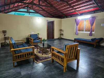 a living room with chairs and a table at Siruvani Forest Farmstay By Shivalaya Stays in Coimbatore