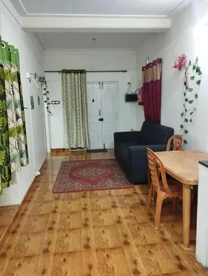 a living room with a table and a blue couch at Arnold Home Stay Ooty in Ooty