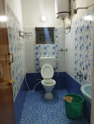 a bathroom with a toilet and a sink and a bucket at Arnold Home Stay Ooty in Ooty