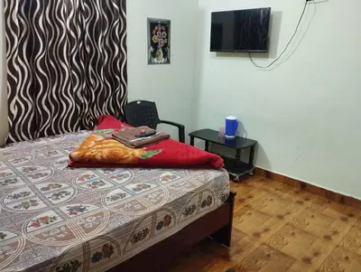 a bedroom with a bed and a tv on the wall at Arnold Home Stay Ooty in Ooty