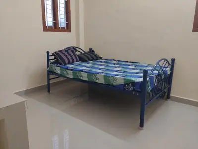 a small bed with a blue frame in a room at Om Cottage in Palani