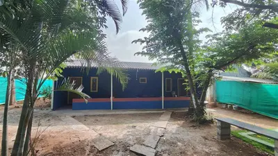 a blue building with trees in front of it at Lavi's Homestay in Hārohalli