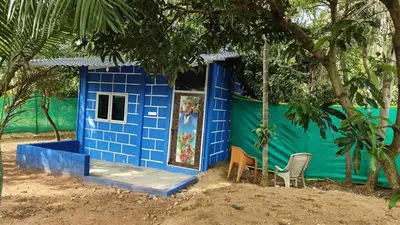 a blue and green house with two chairs in front of it at Lavi's Homestay in Hārohalli