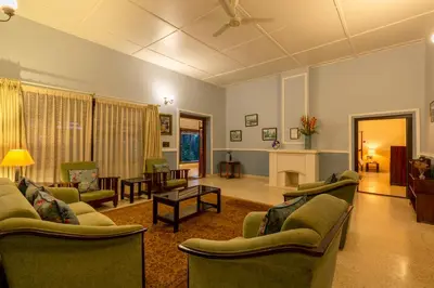a living room with couches and chairs and a table at amã Stays & Trails - Woshully Bungalow, Coorg in Gonikoppal