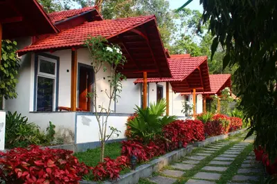 a house with red roofs and red flowers at Aranya Cottage Coorg in Suntikoppa