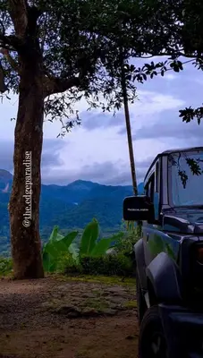 a car parked next to a tree with mountains in the background at The EDGE Paradise in Neriyamangalam