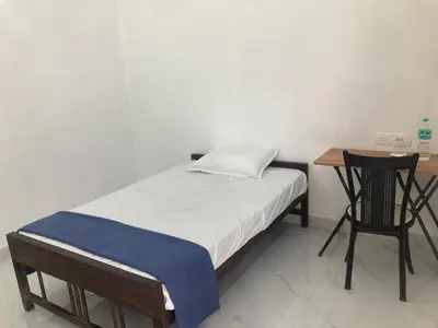 a small bedroom with a bed and a desk at V-host in Alwaye