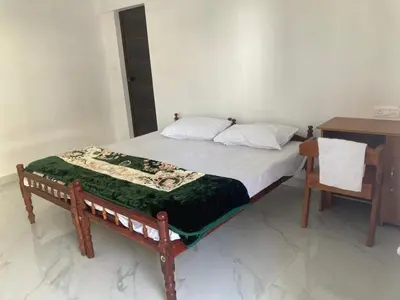 a bed in a room with a desk and a bed sidx sidx sidx at V-host in Alwaye