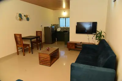 a living room with a couch and a table and a tv at Nirantara Luxury Service Apartment in Gonikoppal