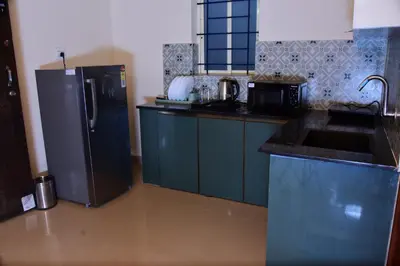 a kitchen with blue cabinets and a black refrigerator at Nirantara Luxury Service Apartment in Gonikoppal