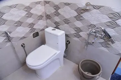 a bathroom with a toilet and a bucket at Nirantara Luxury Service Apartment in Gonikoppal