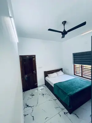 a bedroom with two beds and a ceiling fan at Stay loop in Cherambādi
