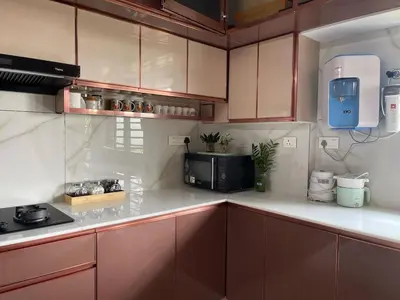 a kitchen with brown cabinets and a microwave at Puranattukara- Serene Stay by the Rice Fields in Trichūr
