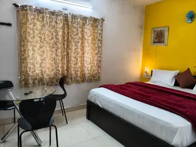 a hotel room with a bed and a table and a desk at White House Resort in Ooty
