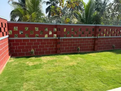 a red brick wall with a green lawn at Dhani Nature Stay in PÄndavapura