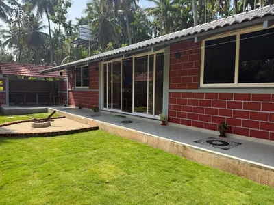 a red brick house with a lawn in front of it at Dhani Nature Stay in PÄndavapura