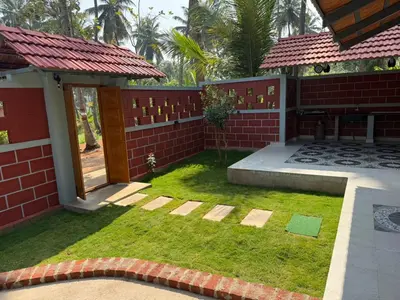 a small yard with a brick wall and grass at Dhani Nature Stay in PÄndavapura