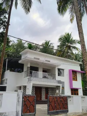 a white house with palm trees in front of it at Riverbend Retreat in Kozhikode