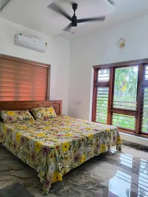 a bedroom with a bed with a floral bedspread at Riverbend Retreat in Kozhikode