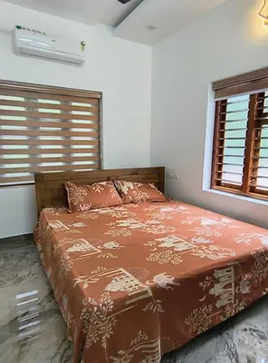 a bedroom with a bed and two windows at Riverbend Retreat in Kozhikode