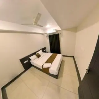 a bedroom with a bed in a white room at Gokulam Suits Guruvayur in Guruvāyūr