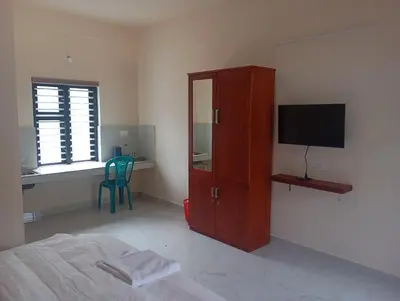 a bedroom with a bed and a cabinet with a television at PURAYIL Rooms in Kozhikode