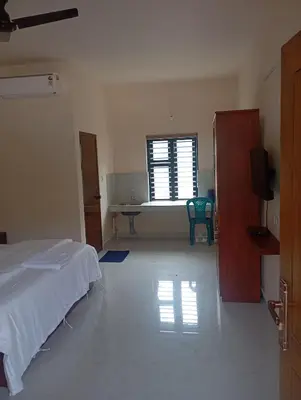a bedroom with a bed and a table and a window at PURAYIL Rooms in Kozhikode