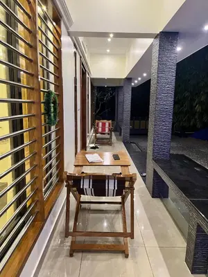 a living room with a table and a chair at Luxury Garden Villa, Free Breakfast in Guruvayoor in Manattala