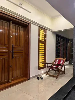 a room with a wooden door and a chair at Luxury Garden Villa, Free Breakfast in Guruvayoor in Manattala