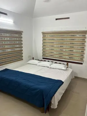 a bedroom with a large bed with two windows at Entire 4BHK House with Full Kitchen near malayattoor in Kodanad