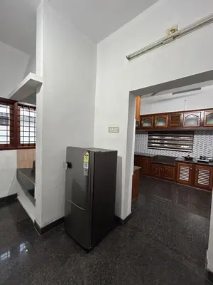 a kitchen with a refrigerator in the middle of a room at Entire 4BHK House with Full Kitchen near malayattoor in Kodanad