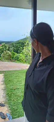 a woman looking out of a window at the grass at Metta Heaven in Kodenchery