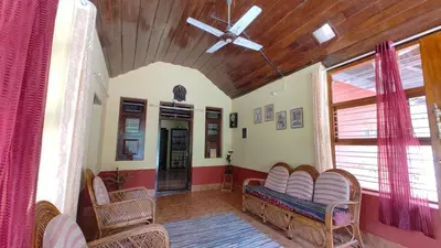 a living room with chairs and a ceiling fan at Heritage Mudhouse Homestay in Virajpet