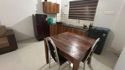 a kitchen with a wooden table and a black refrigerator at 1bhk Kalp 200m temple Thulasi nagar in Guruvāyūr
