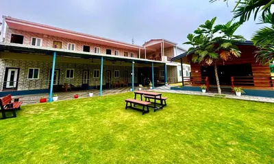 a green yard with two benches in front of a building at BR Farm Stay in Coimbatore