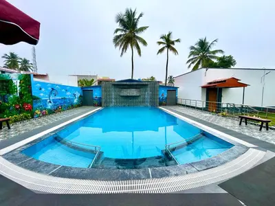 a large swimming pool in a building with palm trees at BR Farm Stay in Coimbatore