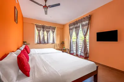 a bedroom with a large white bed with red pillows at Orchid Villa Kotagiri in Kodanād