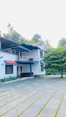 a large white building with a patio in front of it at The Wayanad Stays in Kalpetta