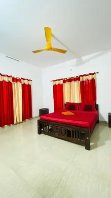 a red bed in a room with red curtains at The Wayanad Stays in Kalpetta
