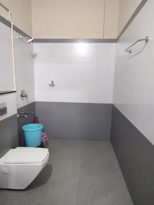 a bathroom with a toilet and a blue bucket at Bridgettine Paradise in Sultan Bathery